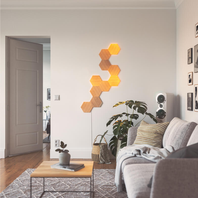 Nanoleaf Elements Thread-enabled wood-look hexagon smart modular light panels mounted to a wall in a living room. HomeKit, Google Assistant, Amazon Alexa, IFTTT.